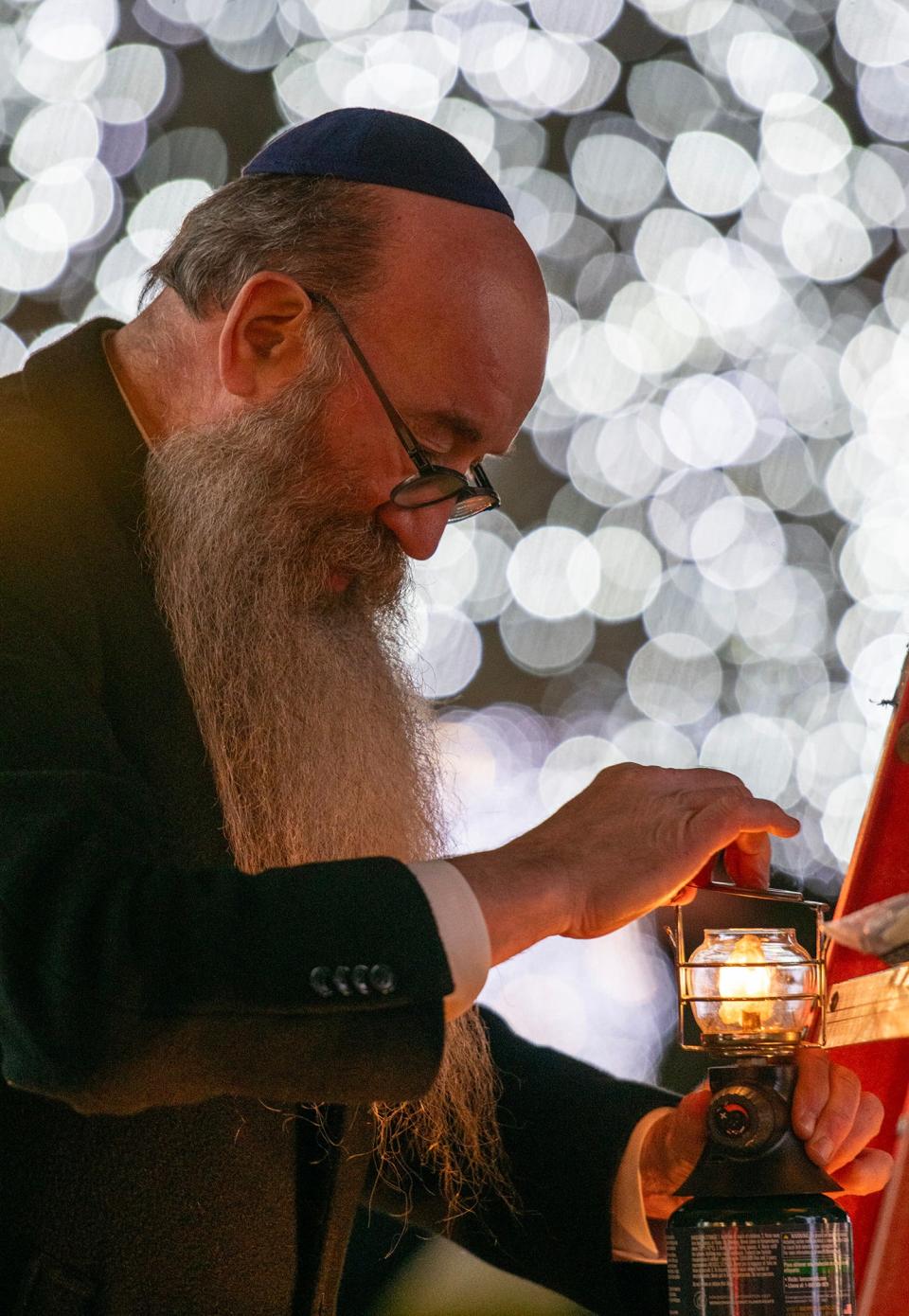 Rabbi Levi Liberow lights a propane lantern that will be placed on the Worcester Common menorah Tuesday.
