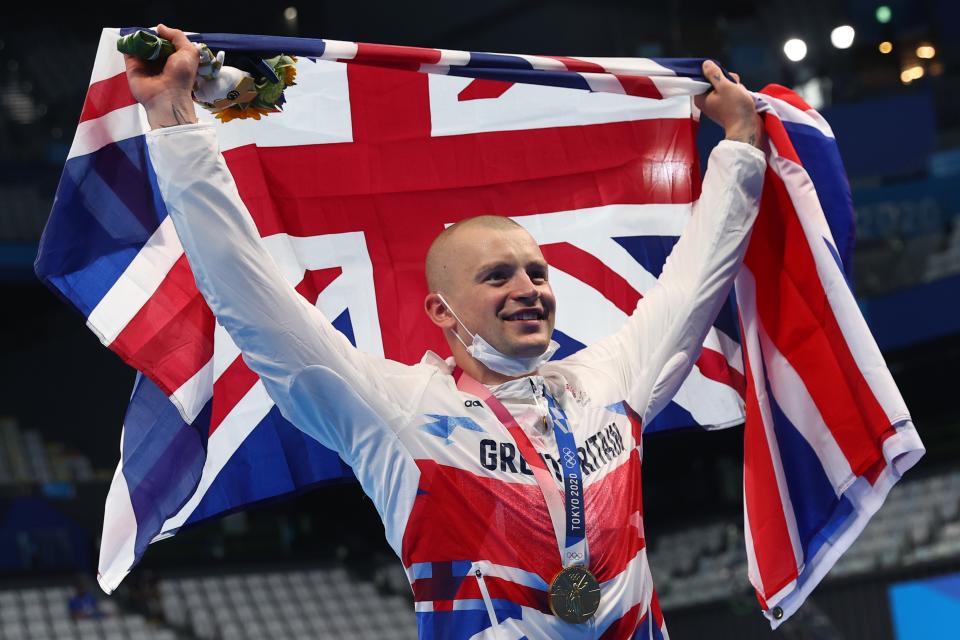 Adam Peaty holds up the British flag after winning Team GB's first gold at Tokyo 2020