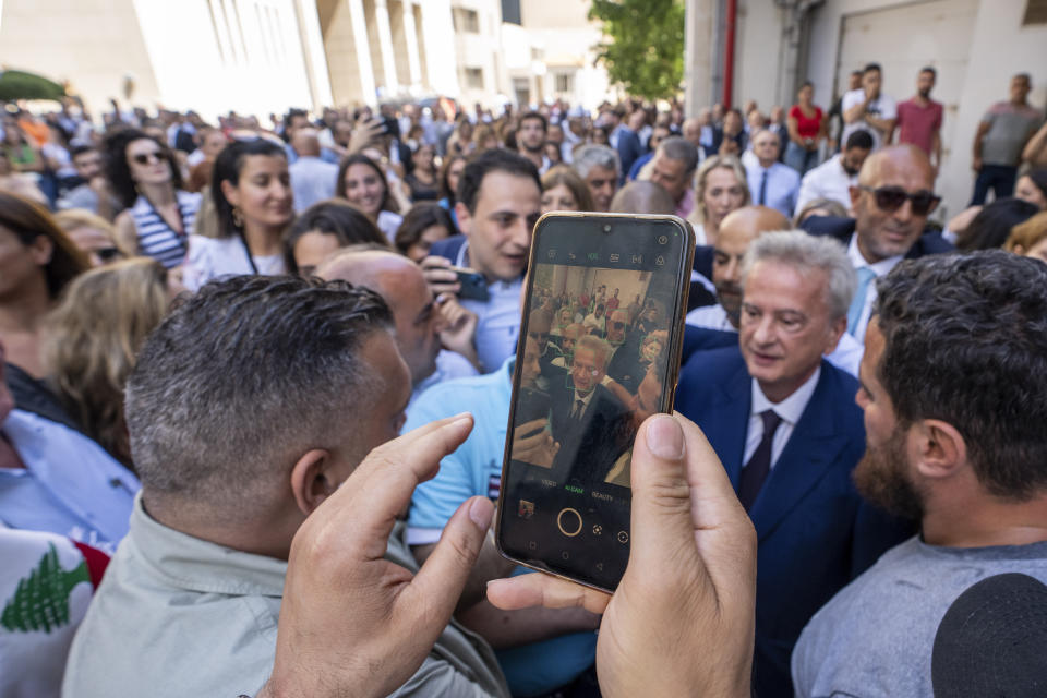 Riad Salameh, second right, Lebanon's outgoing Central Bank governor, greets employees at a farewell ceremony marking the end of his 30 years in office outside the Central Bank building, in Beirut, Monday, July 31, 2023. Meanwhile, his four vice governors, led by incoming interim governor Wassim Mansouri, urged the cash-strapped country's government for fiscal reforms at a news conference in that same building. (AP Photo/Hassan Ammar)