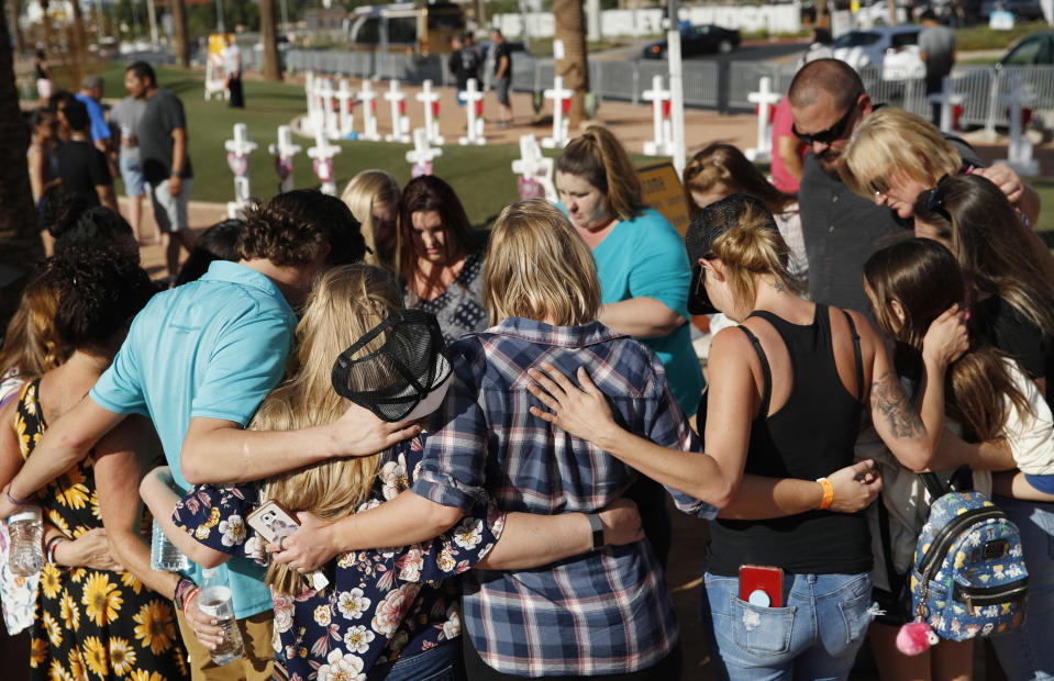FILE - In this Sept. 30, 2018 file photo people pray at a makeshift memorial for victims of the Oct. 1 2017 mass shooting in Las Vegas. The federal government is allocating nearly $17 million to help people affected by the Las Vegas Strip mass shooting that became the deadliest in the nation's modern history, acting U.S. Attorney General Matthew Whitaker said Friday, Nov. 30, 2018. (AP Photo/John Locher, File)