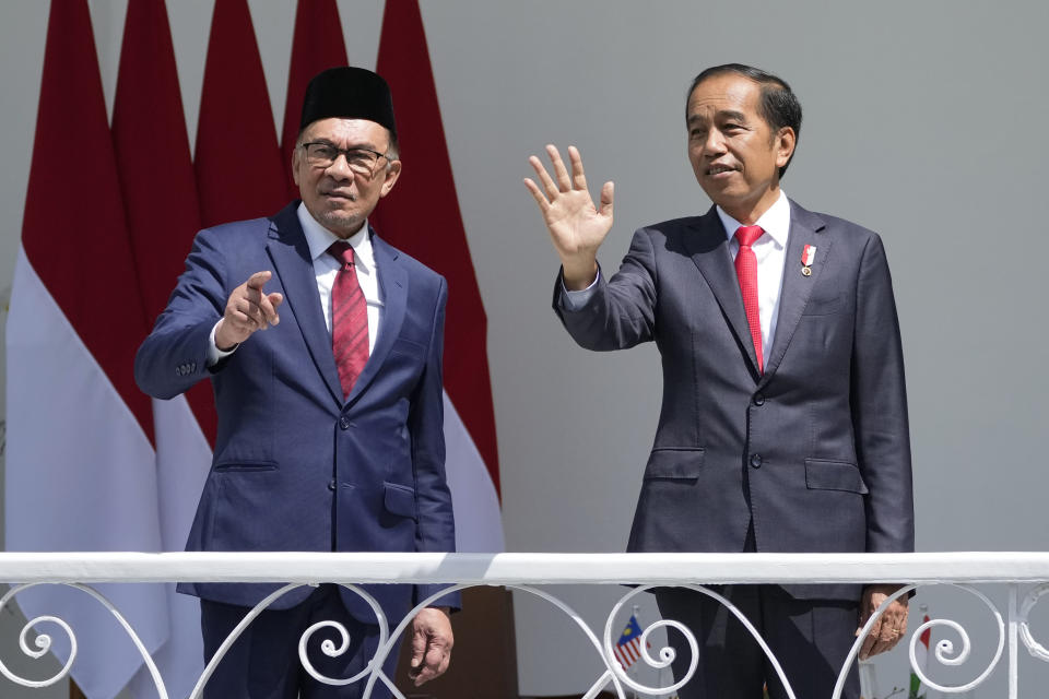 Indonesian President Joko Widodo, right, and Malaysia's Prime Minister Anwar Ibrahim wave at journalists during their meeting at the presidential palace in Bogor, West Java, Indonesia, Monday, Jan. 9, 2023. (AP Photo/Achmad Ibrahim)