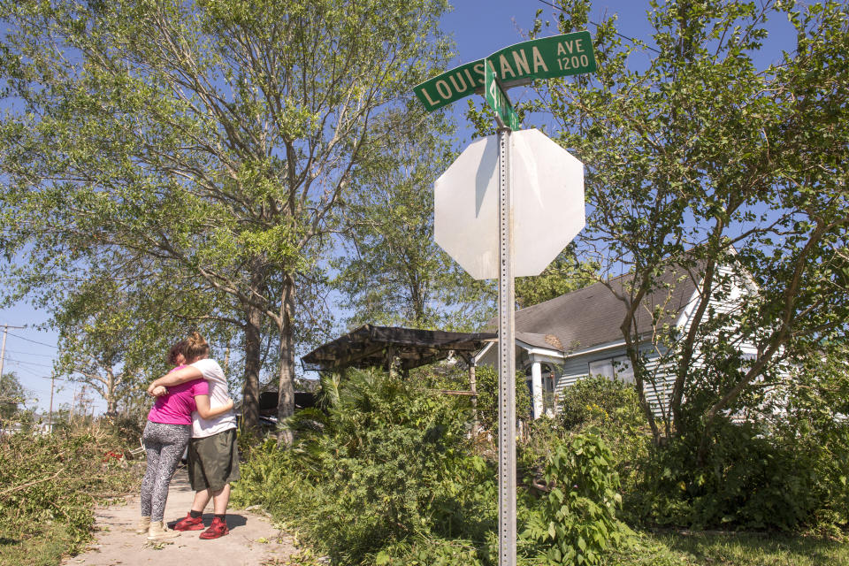 Adam Butler, 17, hugs his girlfriend, Eowyn Greene, 16, while standing on Louisiana Street in Lake Charles, La., as they and their families clean up their yards and houses following Hurricane Delta on Saturday, Oct. 10, 2020. (Chris Granger/The Advocate via AP)