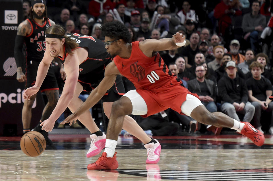 Toronto Raptors forward Kelly Olynyk, left, and Portland Trail Blazers guard Scoot Henderson reach for the ball during the second half of an NBA basketball game in Portland, Ore., Saturday, March 9, 2024. (AP Photo/Steve Dykes)