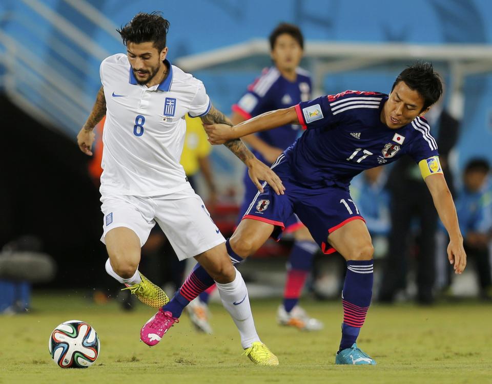 Japan's Makoto Hasebe fights for the ball with Greece's Panagiotis Kone (L) during their 2014 World Cup Group C soccer match at the Dunas arena in Natal June 19, 2014. REUTERS/Sergio Moraes