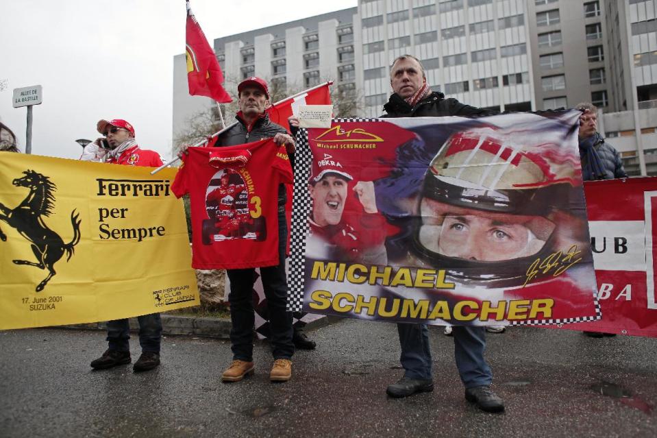 Fans of Michael Schumacher hold banners to honor the Formula One Champion on his 45th birthday, Friday Jan. 3, 2014, in front of the Grenoble hospital where former seven-time Formula One champion Michael Schumacher is being treated after sustaining a head injury during a ski accident. Schumacher has been in a medically induced coma since Sunday, when he struck his head on a rock while on a family vacation. (AP Photo/Thibault Camus)