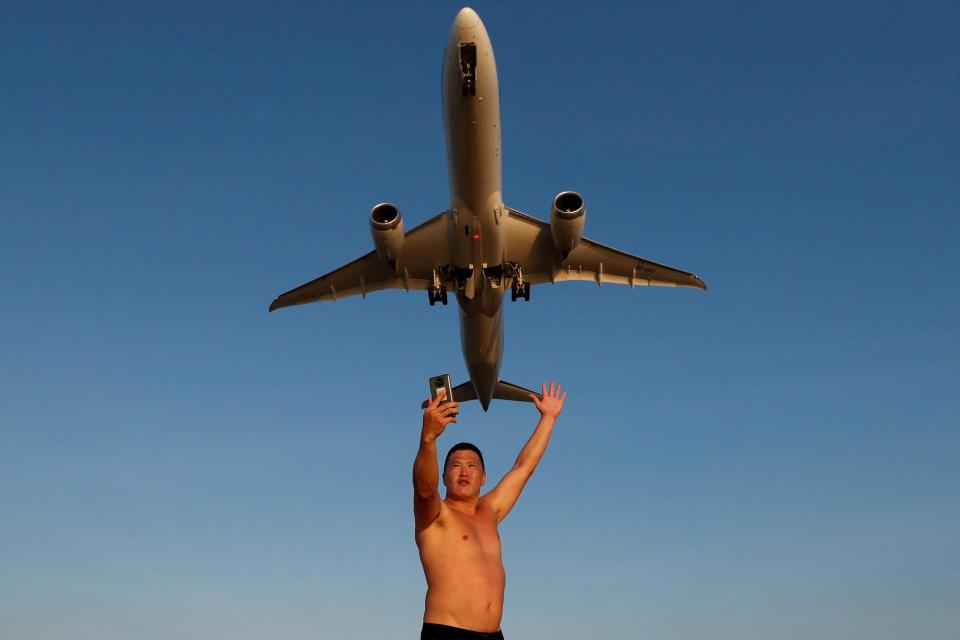 Ivan, a tourist from Russia, takes a selfie at Mai Khao Beach as a plane takes off from Phuket International Airport in Phuket, Thailand, January 17, 2022.  TPX IMAGES OF THE DAY