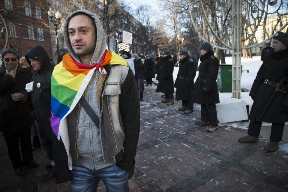 FILE - In this Sunday, Jan. 19, 2014 file photo a Russian gay rights activist walks along a police line during a rally at a Moscow boulevard. When the Sochi Winter Olympics begin on Friday, Feb. 7, 2014, many will be watching to see whether Russia will enforce its law banning gay “propaganda” among minors if athletes, fans or activists wave rainbow flags or speak out in protest. The message so far has been confusing. (AP Photo/ Alexander Zemlianichenko, file)