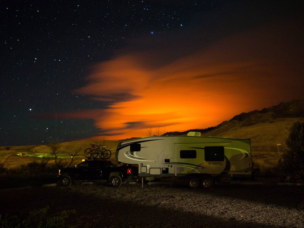 A trailer parked at a campground in Savona, B.C., is seen as the Elephant Hill wildfire burns in the distance near Clinton, B.C., in late July 2017. The fire directly affected numerous First Nations. (Darryl Dyck/The Canadian Press - image credit)