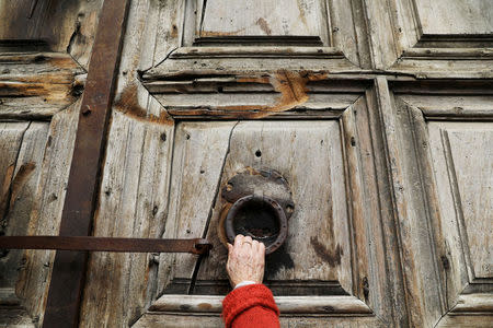 A worshipper touches the closed doors of the Church of the Holy Sepulchre in Jerusalem's Old City February 27, 2018. REUTERS/Ammar Awad