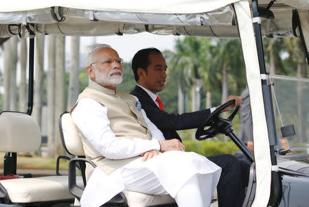 Indian Prime Minister Narendra Modi sits as Indonesia President Joko Widodo drives golf cart at National Monument in Jakarta, Indonesia May 30, 2018. REUTERS/Beawiharta