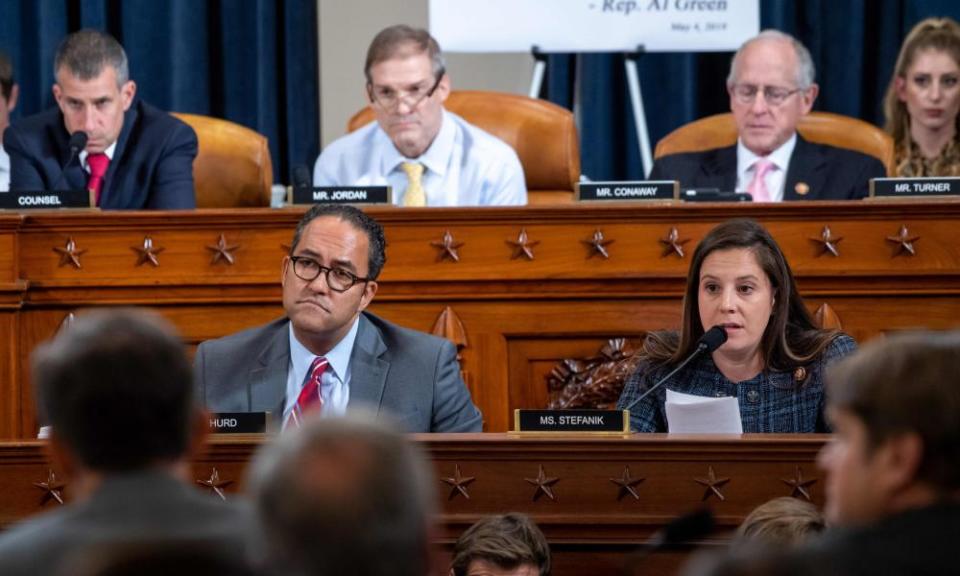 stefanik sits behind a mic at a desk, with other congresspeople around her