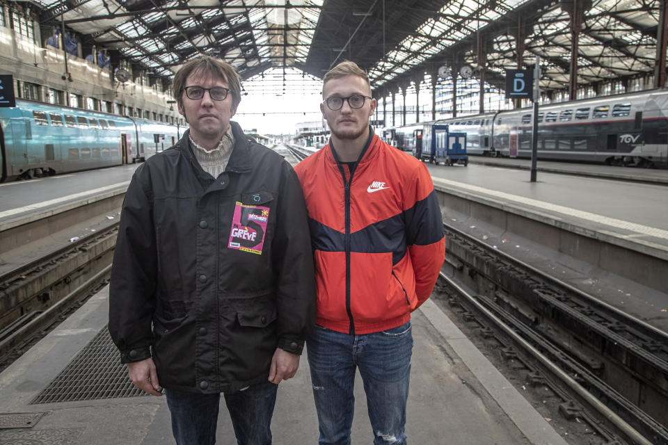 In this photo taken Saturday Nov. 30, 2019, Gilles Pierre, left, a metro driver for the Paris public transport company RATP, and Vincent Le Faucheur, 23, a train traffic controller for the national railway company SNCF pose at the Gare de Lyon train station in Paris. France is getting ready for massive, nationwide transport strikes Thursday, disrupting trains, buses and airlines, protesting against government plans to overhaul the state pension system. (AP Photo/Michel Euler)