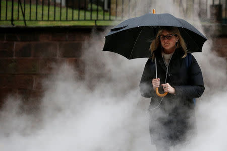 A woman is surrounded by steam as she crosses the street in the financial district during a winter nor'easter in New York City, U.S., January 24, 2017. REUTERS/Brendan McDermid