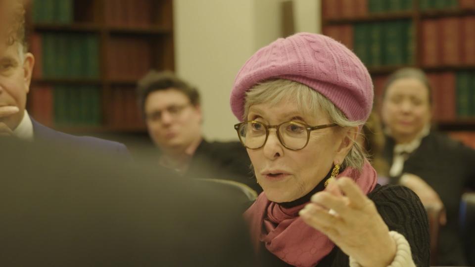 Rita Moreno speaks while wearing a pink hat