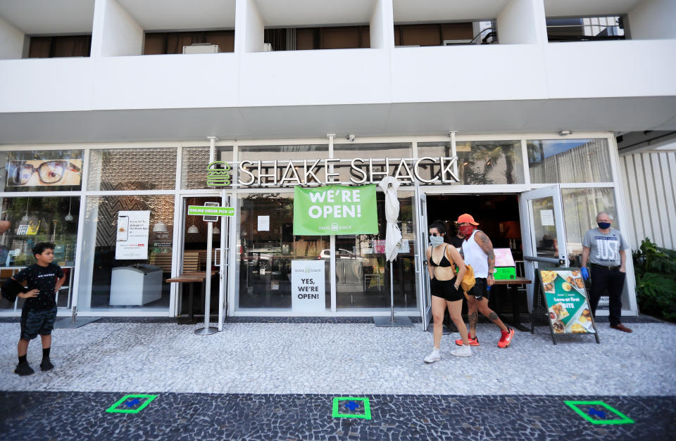 MIAMI BEACH, FLORIDA - APRIL 19: Customers wait for to-go orders outside Shake Shack in South Beach on April 19, 2020 in Miami Beach, Florida. Miami Beach restaurants are restricted to take-away and delivery orders due to the COVID-19 Pandemic.  (Photo by Cliff Hawkins/Getty Images)