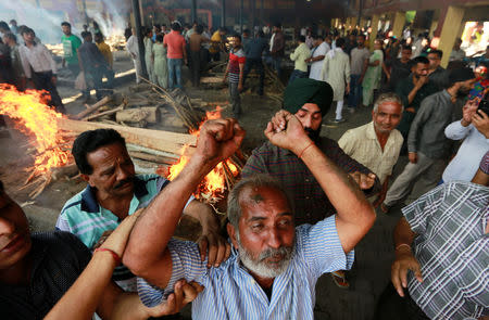 A man mourns next to the burning pyre of a family member who died after a commuter train traveling at high speed ran through a crowd of people on the rail tracks on Friday, at a cremation ground in Amritsar, India, October 20, 2018. REUTERS/Adnan Abidi