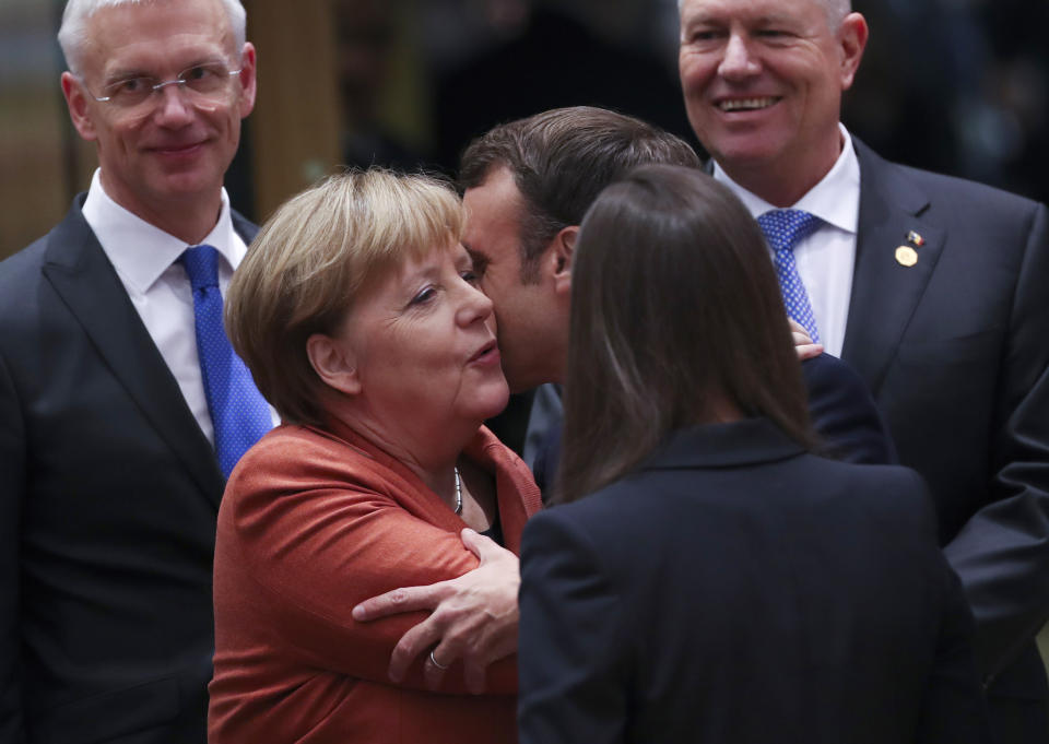 German Chancellor Angela Merkel, second left, is greeted by French President Emmanuel Macron, third right, during a round table meeting at an EU summit in Brussels, Thursday, Dec. 12, 2019. European Union leaders gather for their year-end summit and will discuss climate change funding, the departure of the UK from the bloc and their next 7-year budget. (AP Photo/Francisco Seco)