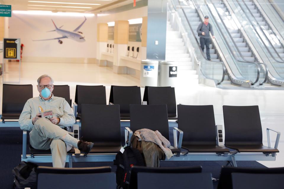 A traveler wears a mask while reading in John F. Kennedy International Airport in New York City. The CDC has advised that people on public conveyances — including trains, planes and buses — wear masks for the entire duration of their trip.  (Lucas Jackson / Reuters)