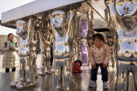 Residents bring their children play on an art installation on display at a mall next to a venue which host the men's and women's ice hockey games at the 2022 Winter Olympics in Beijing, Thursday, Feb. 10, 2022. (AP Photo/Andy Wong)