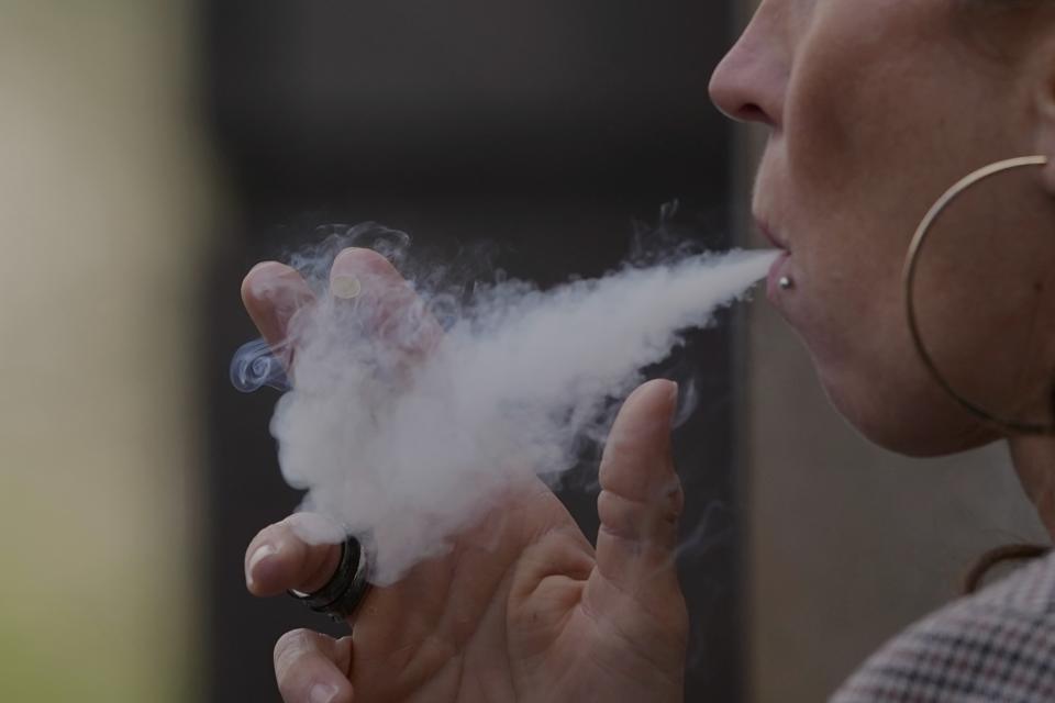 A woman smokes on a street, in London, Tuesday, April 16, 2024. A bold plan to ban anyone born after 2008 from ever legally buying cigarettes in Britain faces its first test in Parliament. The bold plan has divided the governing Conservatives, with some hailing its public health benefits and others condemning it as state overreach. (AP Photo/Kin Cheung)