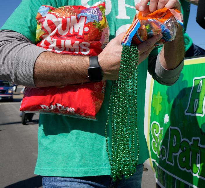 A man hands out lollipops and green beads during the St. Patrick's Day parade through downtown Columbus Thursday. The parade returned this year after a two-year hiatus due to the COVID-19 pandemic.