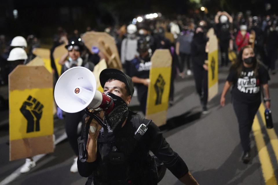 CORRECTS DAY TO FRIDAY - A protester leads a crowd of demonstrators toward the Multnomah County Sheriff's Office on Friday, Aug. 7, 2020 in Portland, Ore. (AP Photo/Nathan Howard)