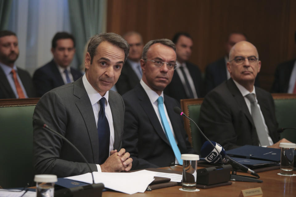 Greek Prime Ministers Kyriakos Mitsotakis, left, speaks next to Finance Minister Christos Staikouras, center, and Greek Foreign Minister Nikos Dendias as the new government participate in their first cabinet meeting, in Athens, Wednesday, July 10, 2019. Conservative party leader Kyriakos Mitsotakis won Sunday's election on pledges that included making the country more businesses-friendly, cutting taxes and negotiating an easing of draconian budget conditions agreed as part of the country's rescue program. (AP Photo/Petros Giannakouris)