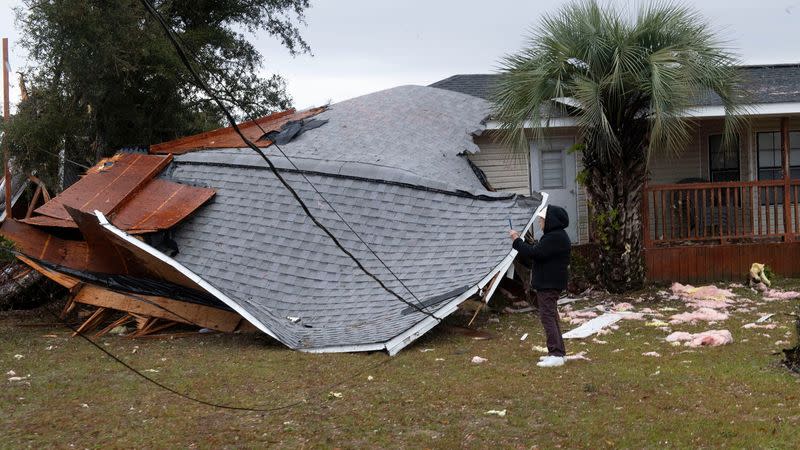 A resident checks a collapsed roof after a line of storms roared through the area of Perdido Key