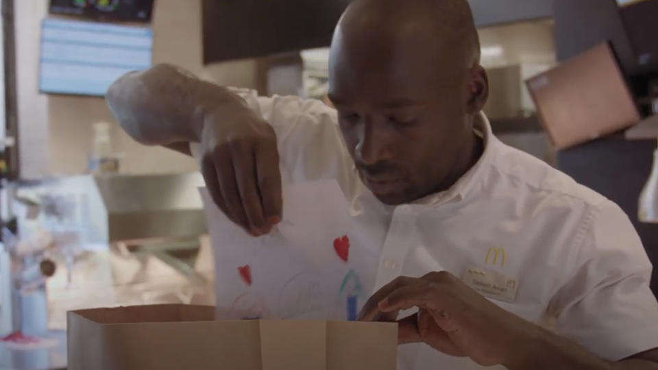 A McDonald's worker places a child's drawing into a delivery bag.