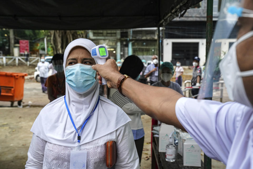 A woman gets her temperature checked before entering a polling station Sunday, Nov. 8, 2020, in Yangon, Myanmar. Voting was underway in Myanmar's elections on Sunday, with the party of Nobel Peace Prize laureate Aung San Suu Kyi heavily favored to retain power it had wrestled from the powerful military five years ago. (AP Photo/Aung Naing Soe)