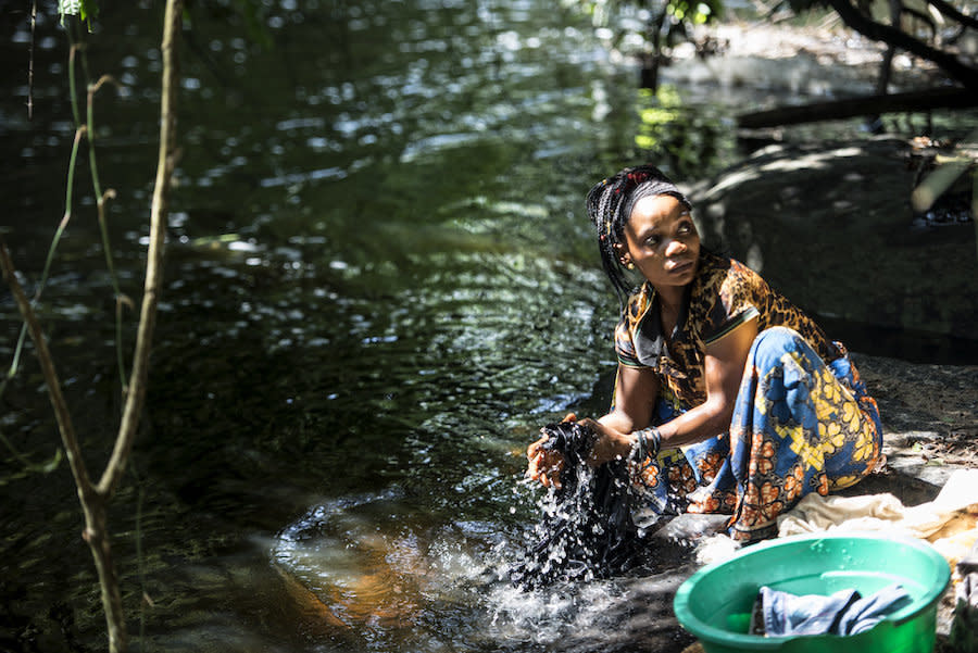 Regine Bora washes clothes by the river while black flies buzz around her. (Photo: Neil Brandvold/DNDi)