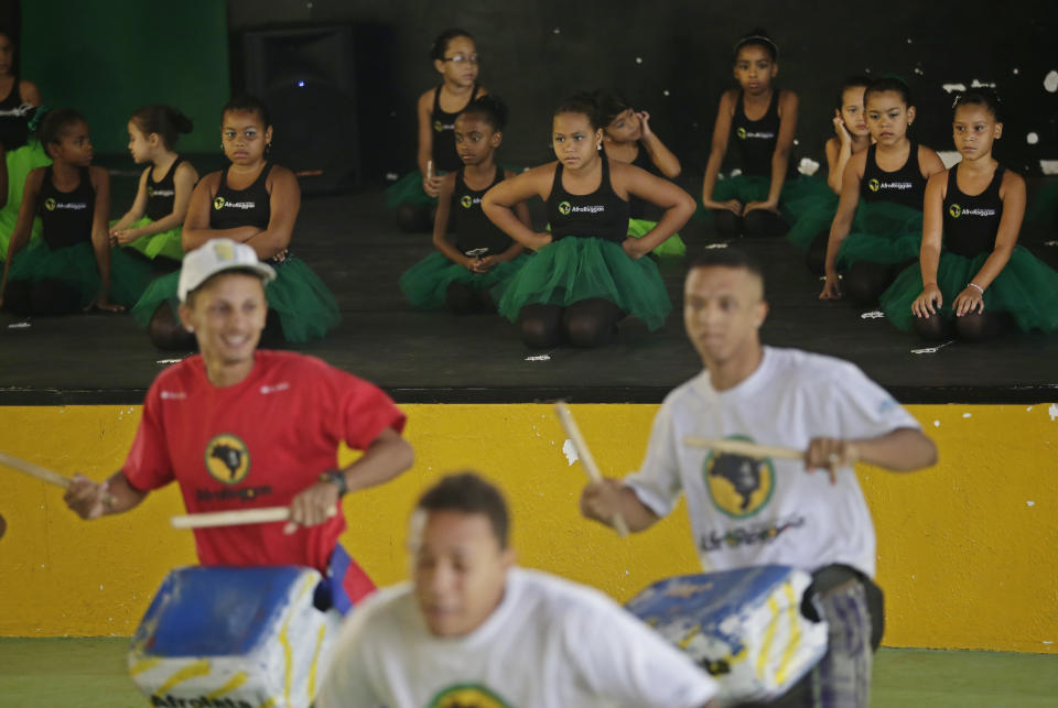 Young dancers watch drum players during a presentation before members of London's Royal Opera House in Vigario Geral slum of Rio de Janeiro, Brazil, Saturday, March 2, 2013. This past week Royal Ballet dancers shared their knowledge and advice with promising artists during an education symposium between the company and the cultural arts center Afro Reggae. (AP Photo/Silvia Izquierdo)