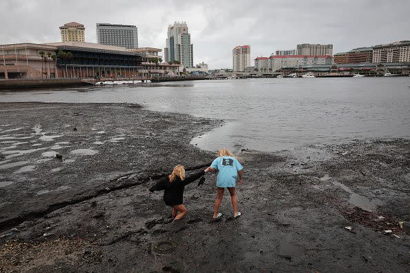 Sisters Angel Disbrow (right) and Selena Disbrow walk along the shore of a receded Tampa Bay as water was pulled out from the bay in advance of the arrival of Hurricane Ian on September 28, 2022, in Tampa, Florida.