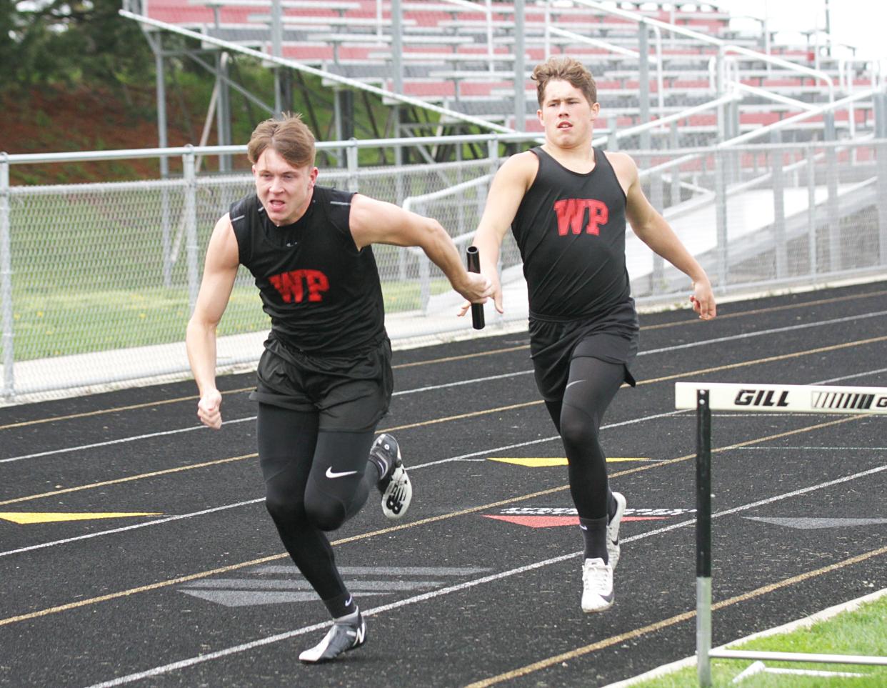 Dylan Carper hands the baton off to Todd Hollingsworth in the 800 relay for White Pigeon on Wednesday.