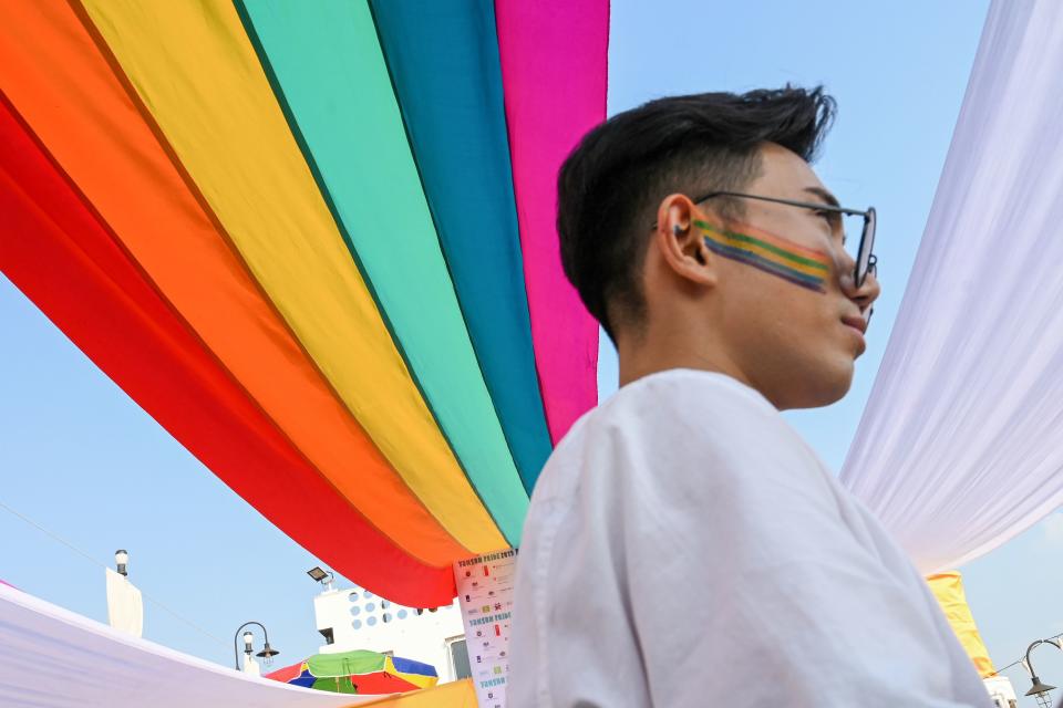 A member of the lesbian, gay, bisexual, and transgender (LGBT) community stands under a rainbow flag displayed on a boat during the Pride Boat Parade, an event of the Myanmar's Yangon Pride festival in Yangon on January 26, 2019. (Photo by YE AUNG THU / AFP) (Photo credit should read YE AUNG THU/AFP via Getty Images)