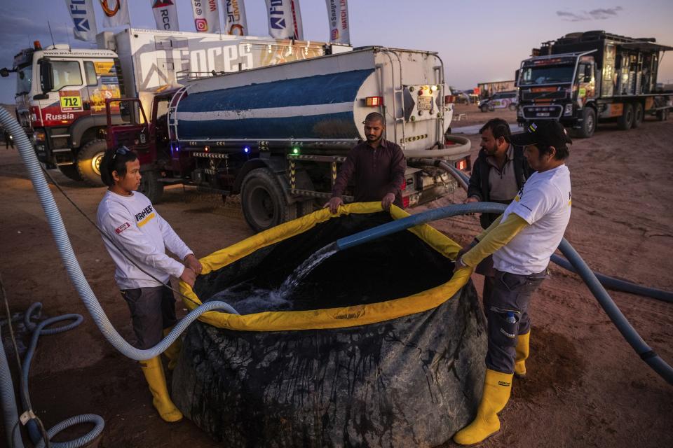 In this Thursday, Jan. 9, 2020 photo, Karcher staffers fill a tank with water to be used for cleaning vehicles at the bivouac of the Dakar Rally in Hail, Saudi Arabia. Formerly known as the Paris-Dakar Rally, the race was created by Thierry Sabine after he got lost in the Libyan desert in 1977. Until 2008, the rallies raced across Africa, but threats in Mauritania led organizers to cancel that year's event and move it to South America. It has now shifted to Saudi Arabia. The race started on Jan. 5 with 560 drivers and co-drivers, some on motorbikes, others in cars or in trucks. Only 41 are taking part in the Original category. (AP Photo/Bernat Armangue)