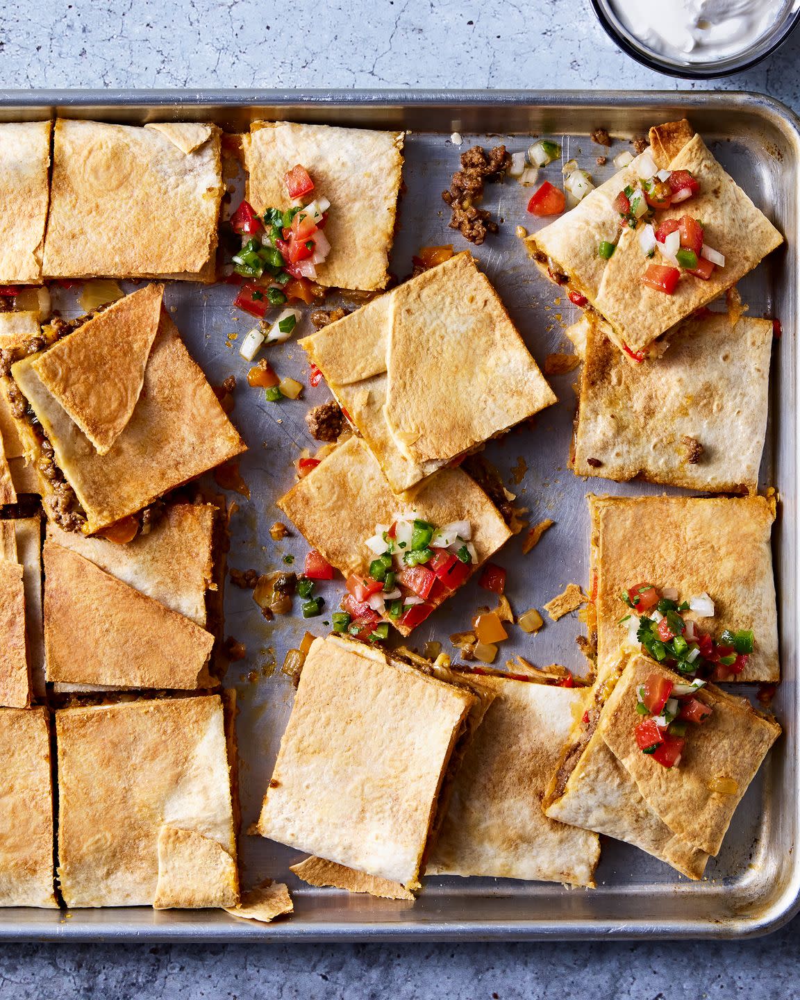 tortillas filled with meat and cheese on a sheet pan