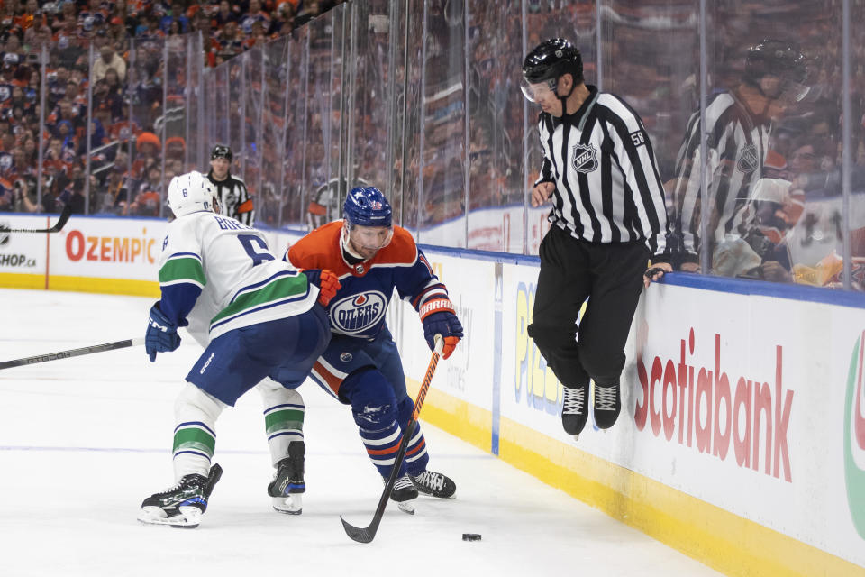 Vancouver Canucks' Brock Boeser (6) checks Edmonton Oilers' Zach Hyman (18) as the linesman jumps out of the way during the second period of Game 3 of an NHL hockey Stanley Cup second-round playoff series in Edmonton, Alberta, Sunday, May 12, 2024. (Jason Franson/The Canadian Press via AP)