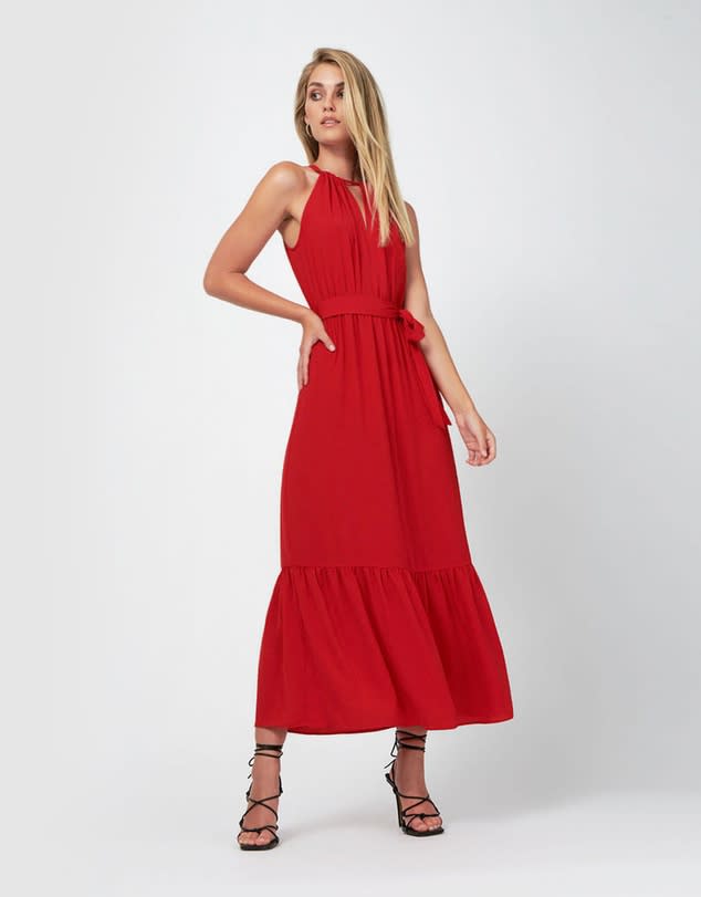 A model stands in a red halter neck dress and black Roman sandals from The Iconic 