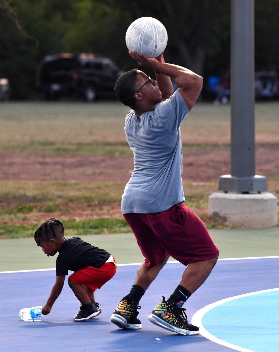 Desmon Williams shoots for the basket as his son Jaxon, 2, retrieves a water bottle on the newly-resurfaced courts at Stevenson Park Friday.