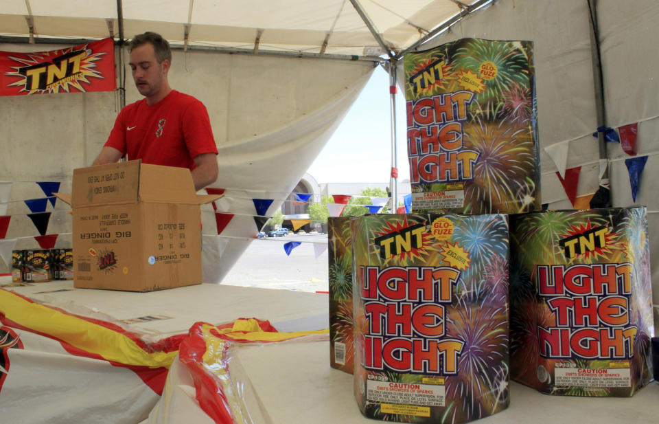 FILE - In this July 1, 2014, file photo, Nathan Farmer unpacks dozens of boxes of fireworks to sell at a roadside stand in Albuquerque, N.M. With fewer professional celebrations on July 4, 2020, many Americans are bound to shoot off fireworks in backyards and at block parties. And they already are: Sales have been booming. (AP Photo/Susan Montoya Bryan, File)