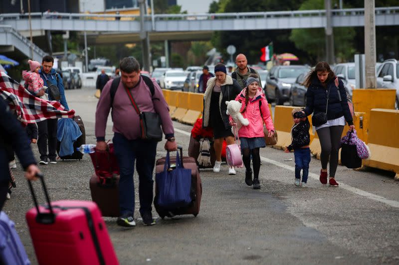 FILE PHOTO: Ukrainians who fled to Mexico amid Russia's invasion of their homeland, walk with their belongings to cross the San Ysidro Land Port of Entry of the U.S.-Mexico border, in Tijuana