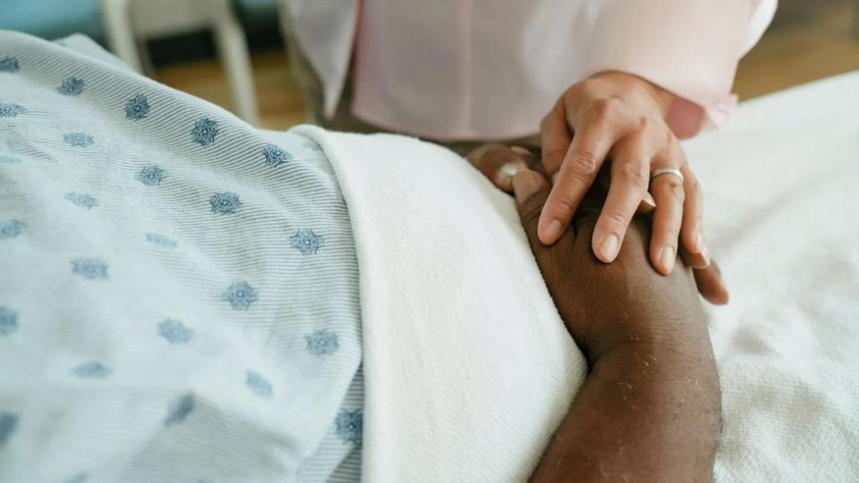 Un médico toca la mano de un paciente.