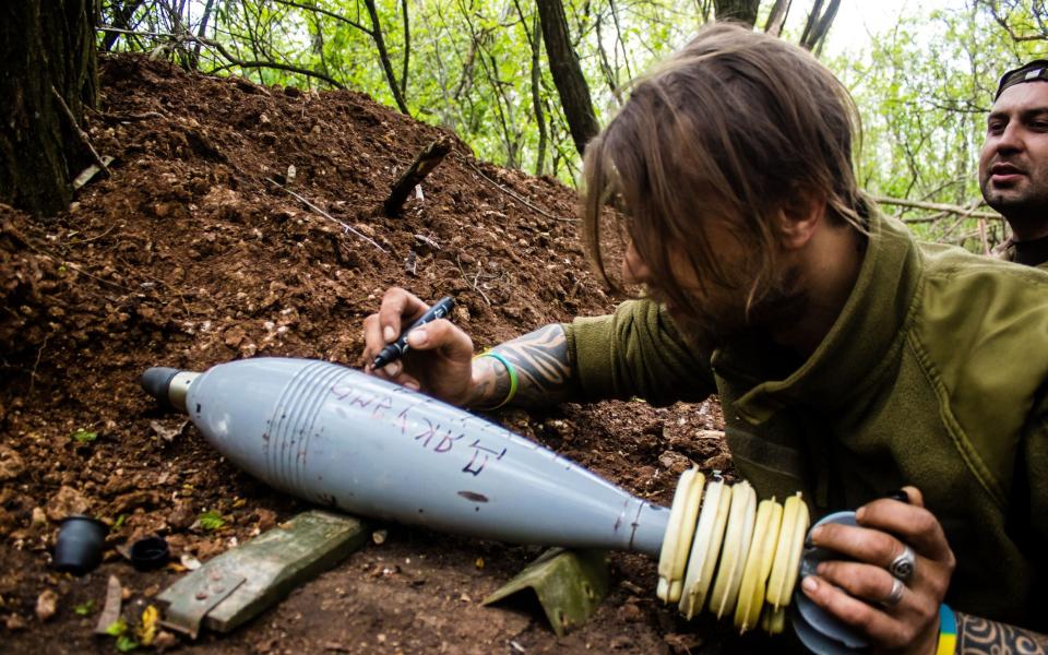 A Ukrainian soldier writes a message on a shell destined for a Russian target near Bakhmut. This practice is very widespread and this action echoes an old tradition. Ukranian soldiers, Bakhmut, Ukraine. - Jose Hernandez/Shutterstock