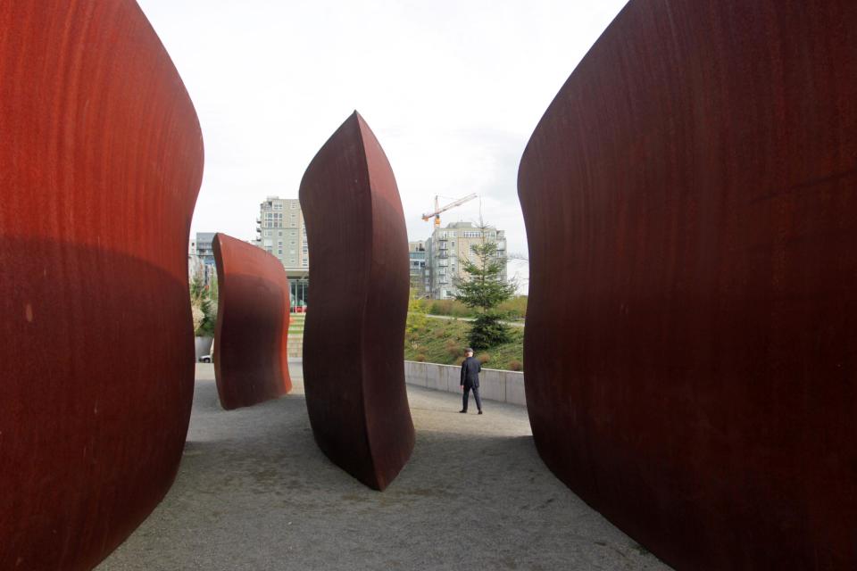 In this image taken April 3, 2013, a man walks past the art installation called "Wake" at the Olympic Sculpture Park in Seattle. The Olympic Sculpture Park, an extension of the Seattle Art Museum, provides visitors the opportunity to relax on its green grass or stroll through its collection of artwork. (AP Photo/Manuel Valdes)