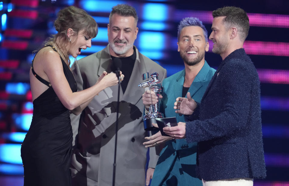 Joey Fatone, centro, Lance Bass, segundo de derecha a izquierda y Justin Timberlake, derecha, de NSYNC entregan el premio de mejor video pop a Taylor Swift por "Anti-Hero" en los Premios MTV a los Videos Musicales el martes 12 de septiembre de 2023 en el Prudential Center en Newark, Nueva Jersey. (Foto Charles Sykes/Invision/AP)