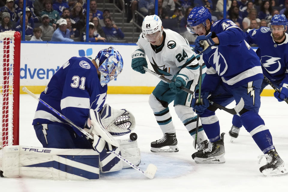 Tampa Bay Lightning goaltender Jonas Johansson (31) makes a save as defenseman Darren Raddysh (43) and San Jose Sharks center Jacob Peterson (24) wait for a rebound during the first period of an NHL hockey game Thursday, Oct. 26, 2023, in Tampa, Fla. (AP Photo/Chris O'Meara)