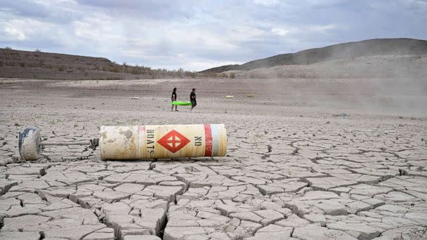 PHOTO: A buoy that reads 'No Boats' lays on cracked dry earth where water once was as people carry a boat further out to reach water at Lake Mead, Nevada, July 23, 2022. (Frederic J. Brown/AFP via Getty Images)