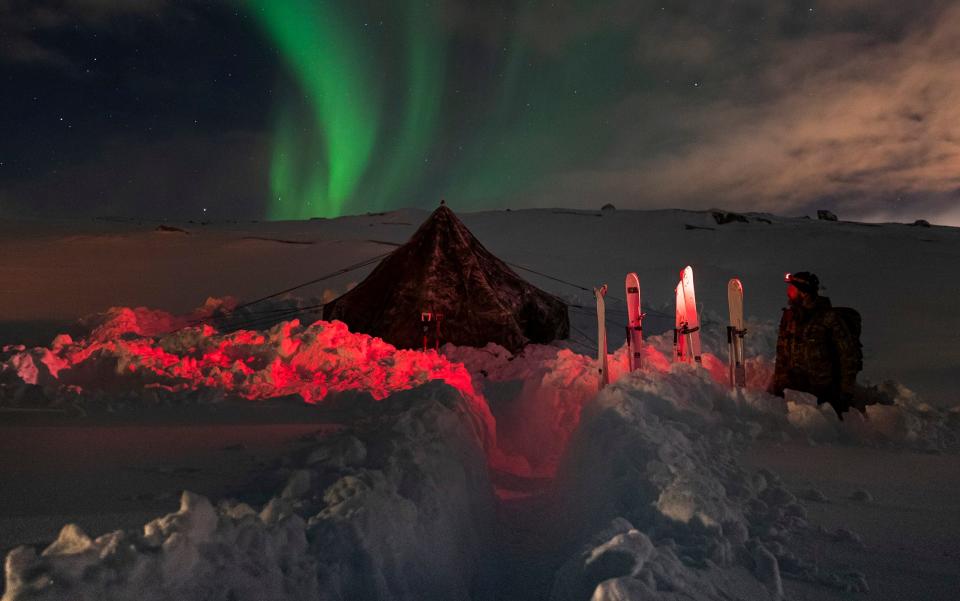 Royal Navy Padre (Russel Fralick) from 45 Commando gazes at the Northern Lights standing next to a ten-man tent wearing a red head torch in Norway, 2021. - LPhot James Clarke/Royal Navy