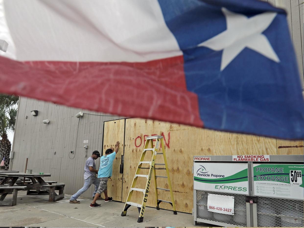 Ramon Lopez, left, and Arturo Villarreal board up windows of a business in Galveston, Texas as Hurricane Harvey intensifies in the Gulf of Mexico: AP Photo/David J. Phillip
